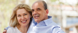 A man and a woman smiling at the camera outside