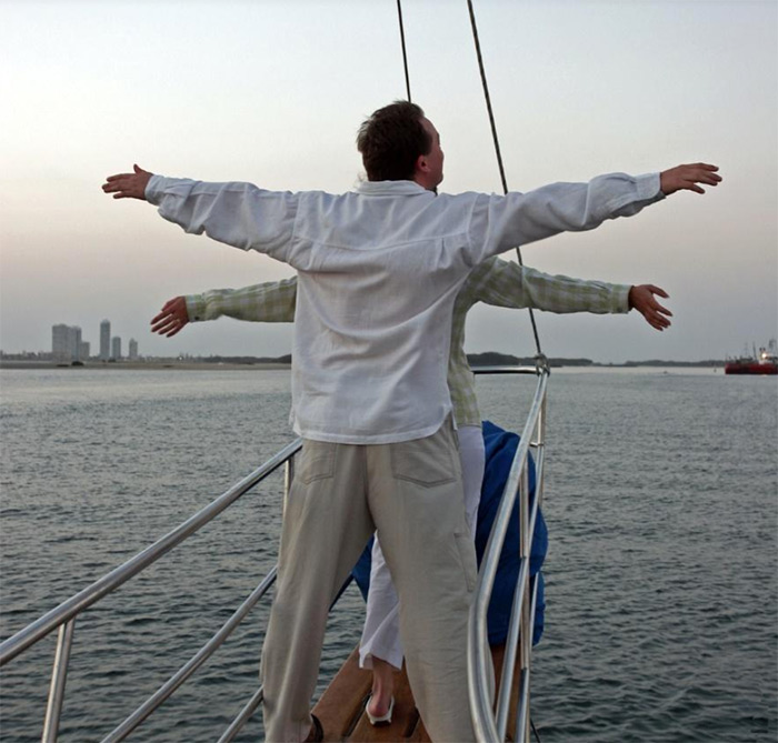 2 people in front of boat with arms outstretched