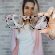 Woman holding glasses in front of Rockville, MD Eye Doctor office.