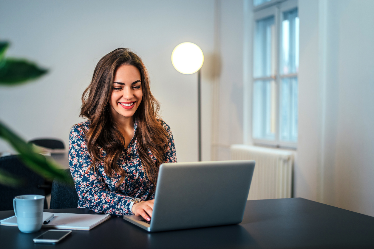 Cheerful woman using laptop for televisit.