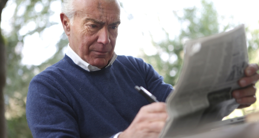 Senior man squinting to read newspaper.