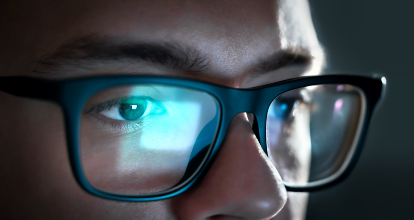 Computer screen light reflect from glasses. Close up of eyes. Business man, coder or programmer working late at night with laptop. Thoughtful focused guy in dark. Reflection of monitor.