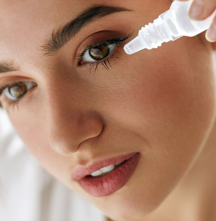 closeup of a woman putting eyedrops in