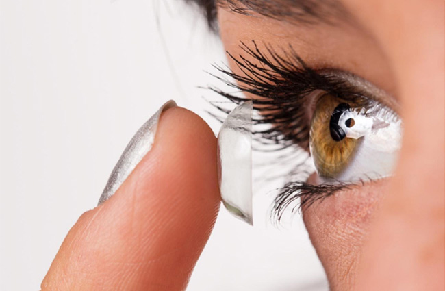 closeup of a woman putting a contact lens in her eye