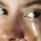 Eye contact from a woman inserting a contact lens into her eye. Macro focus on the lens and eyelash.