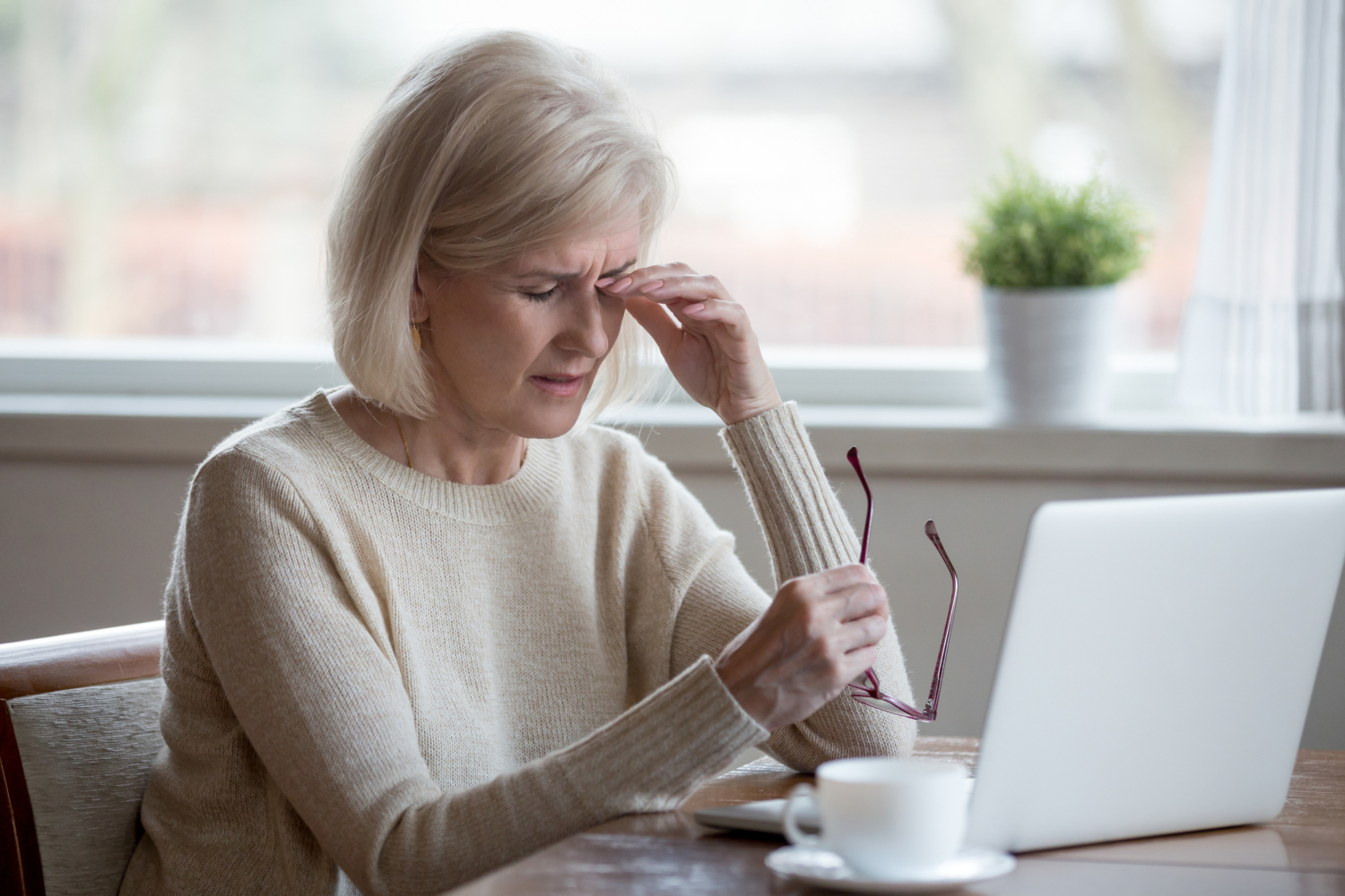 Fatigued mature woman taking off glasses suffering from eye strain