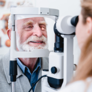 Smiling cheerful elderly patient being checked on eye by female ophthalmic doctor