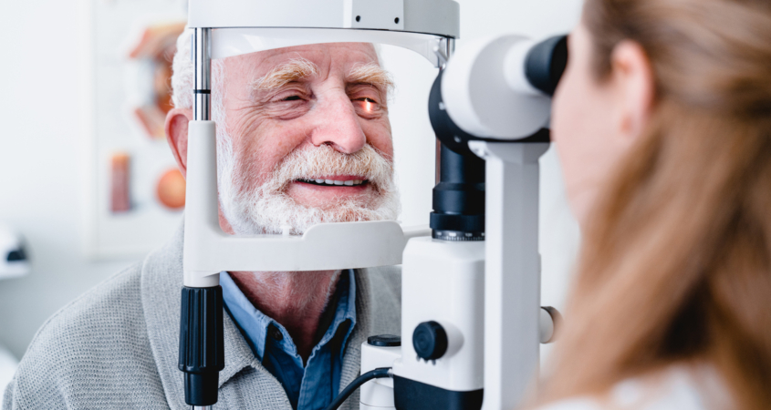 Smiling cheerful elderly patient being checked on eye by female ophthalmic doctor