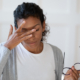 Head shot young stressed unhappy african american woman taking off eyeglasses, feeling tired of long computer work or suffering from dry eyes syndrome, massaging nose bridge, relieving pain.