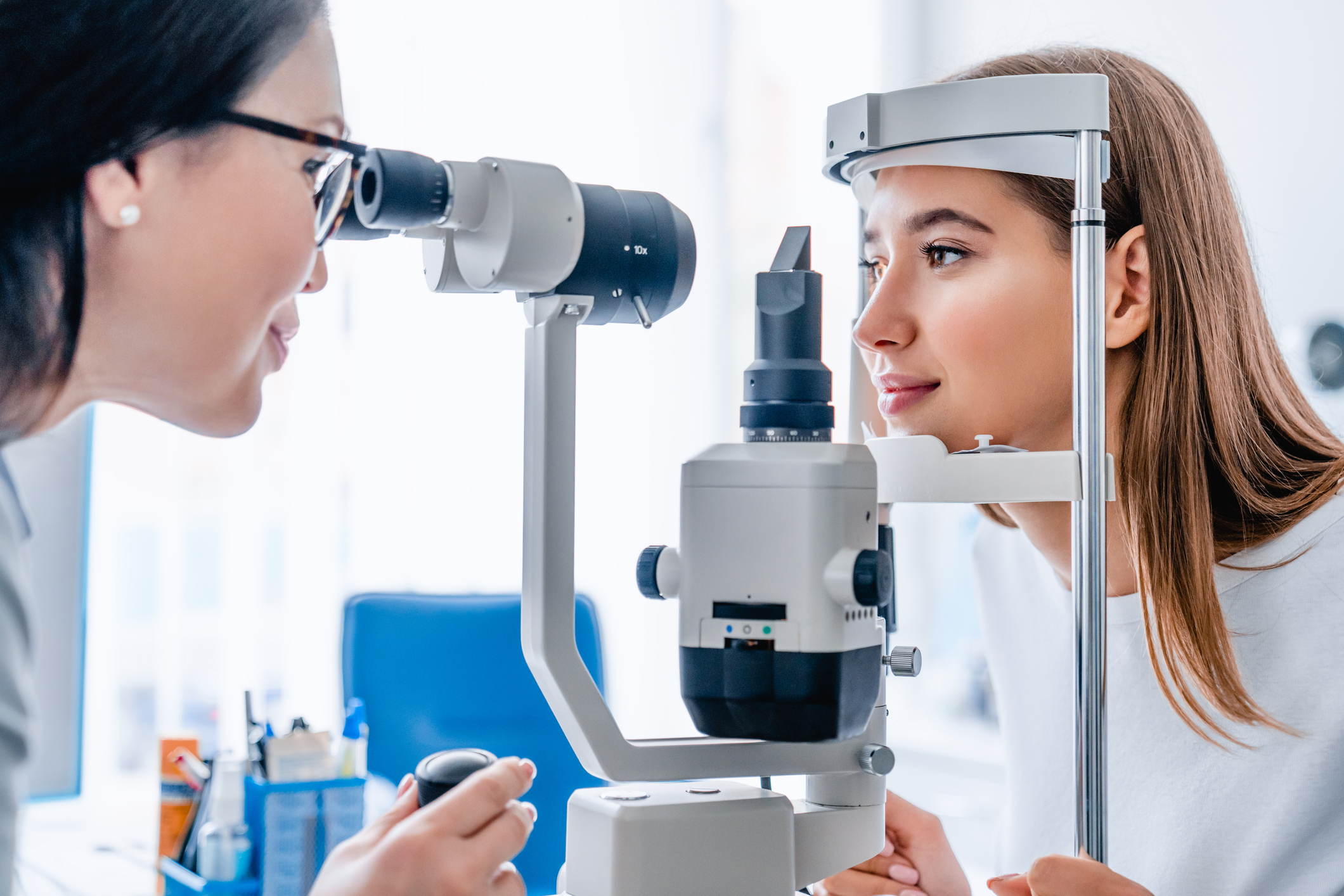 Side view of a woman doing an eye exam with a doctor.