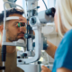 Image of a young man getting his eyes examined by a female optometrist