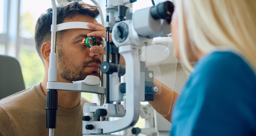Image of a young man getting his eyes examined by a female optometrist