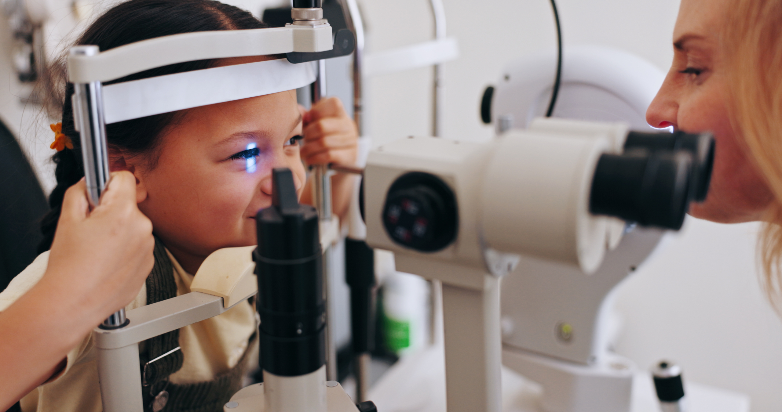 Picture of a pediatric eye doctor giving a young child an eye exam.