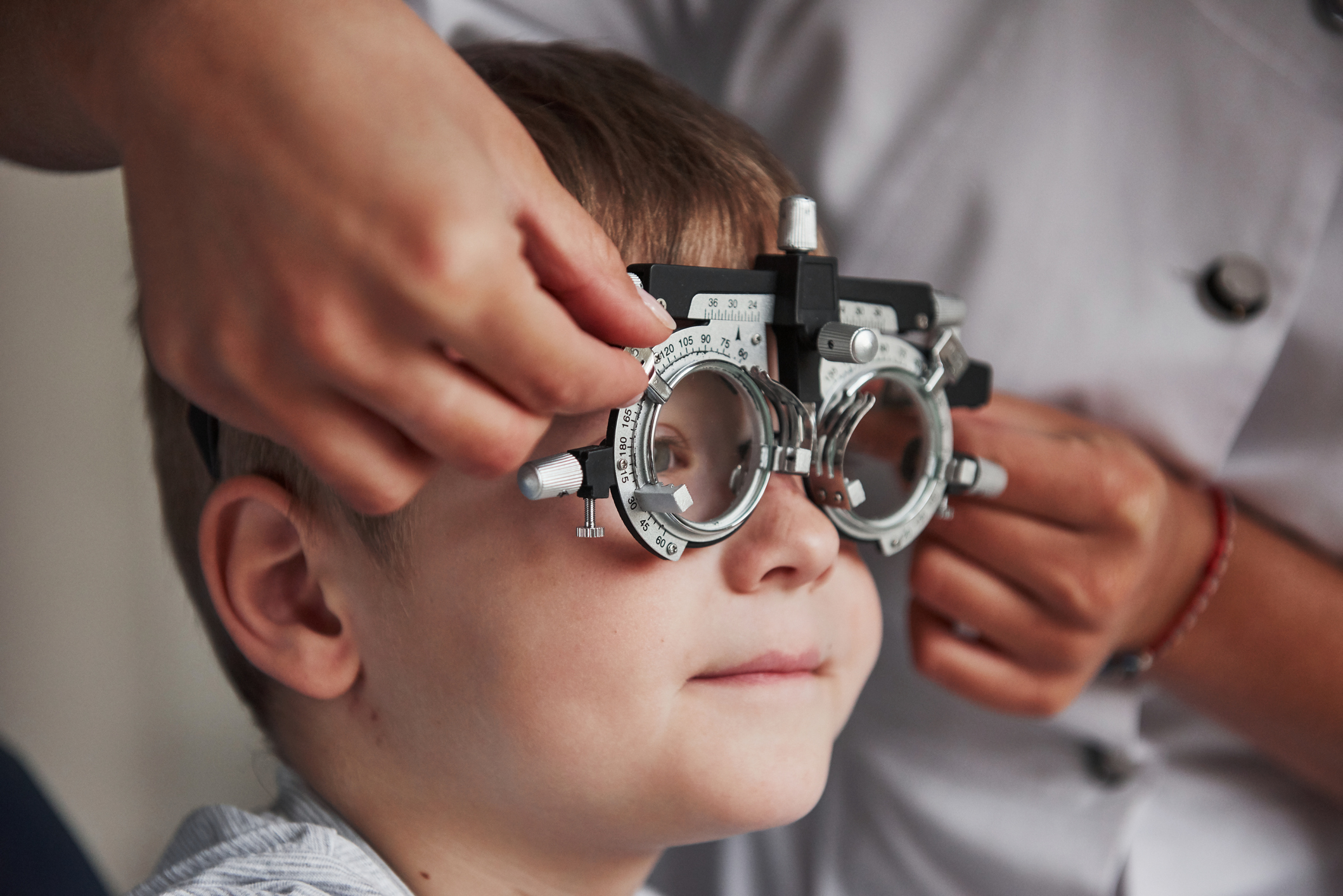 Image of a young boy with vision testing glasses and an optometrist testing his vision.