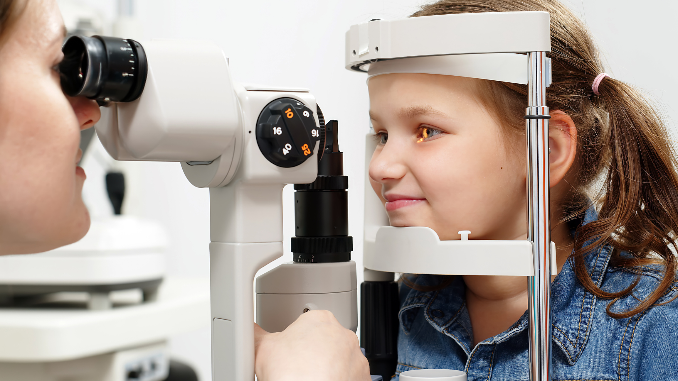 Image of a young girl getting a vision exam during pediatric eye care.