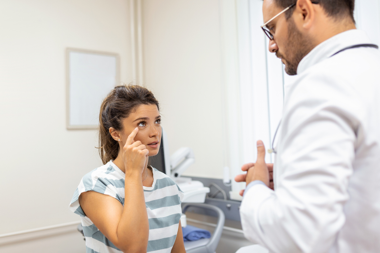 woman speaking with male doctor pointing at her eye