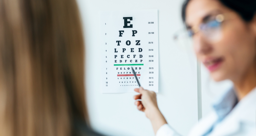 Image of eye doctor pointing to eye chart, testing patient.