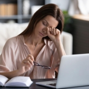 woman itching eyes at laptop