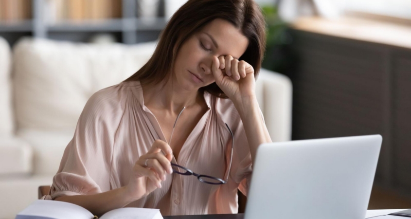 woman itching eyes at laptop