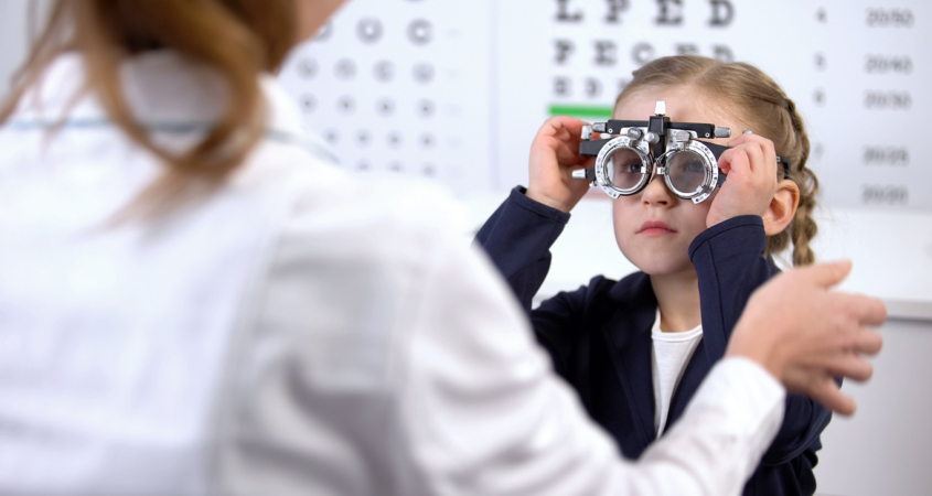 girlvisiting oculist for measuring eyesight with phoropter