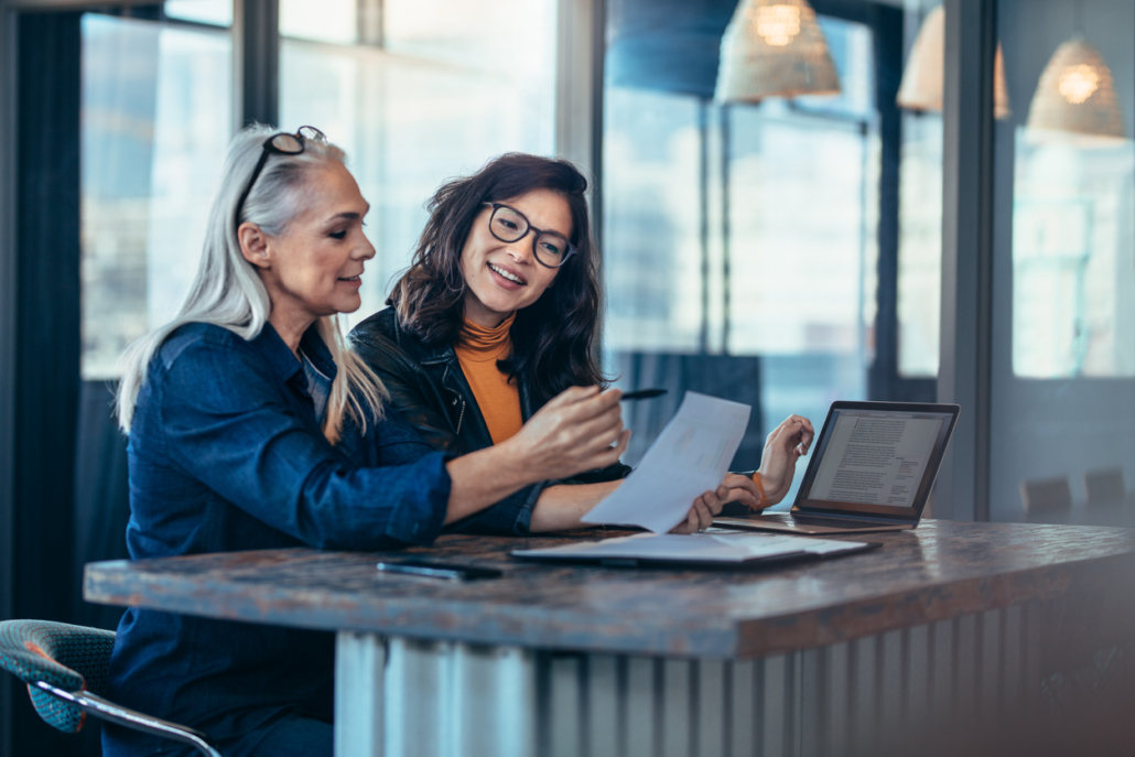 Two women analyzing documents at office Two women analyzing documents at office